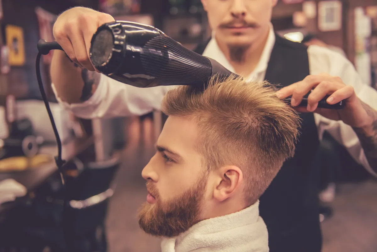 Fryzjer wysusza włosy klienta