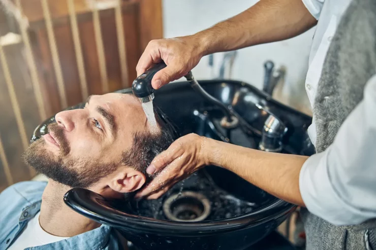 Fryzjer myje głowę klienta